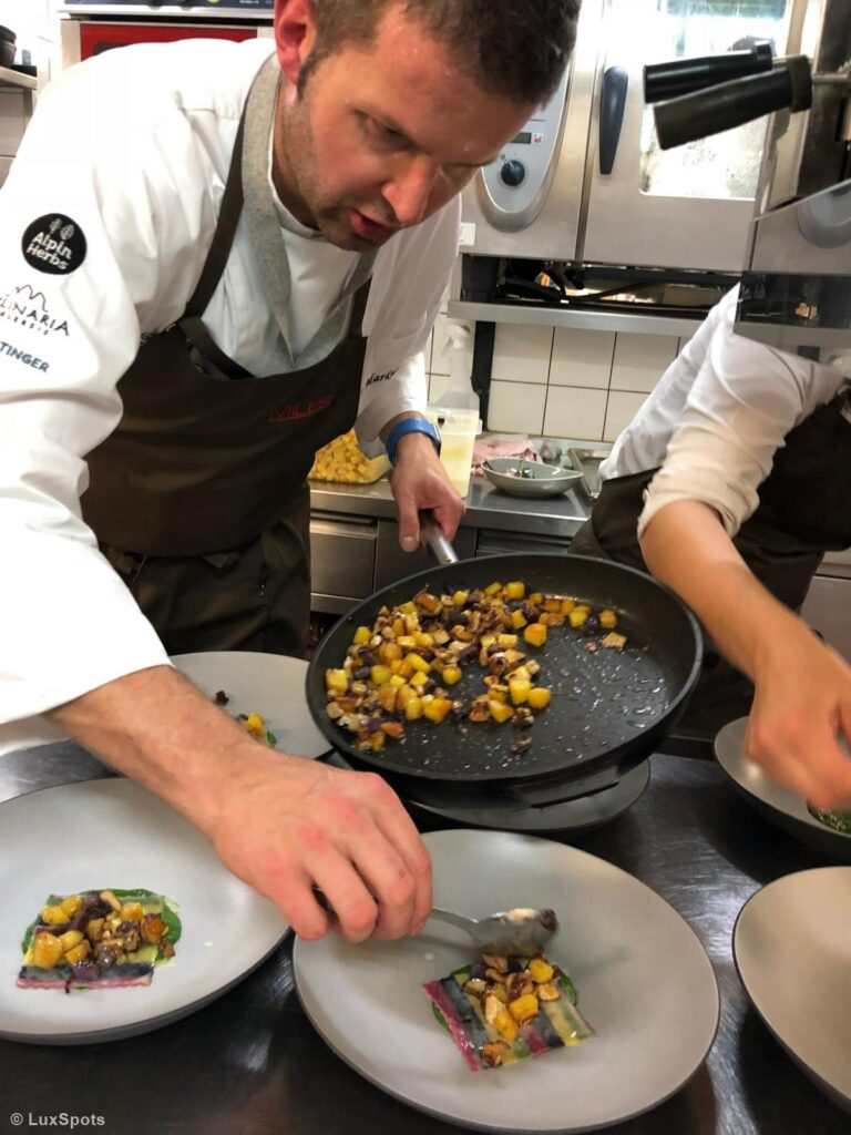 Koch richtet in einer professionellen Küche ein Gericht mit sautiertem Gemüse an.