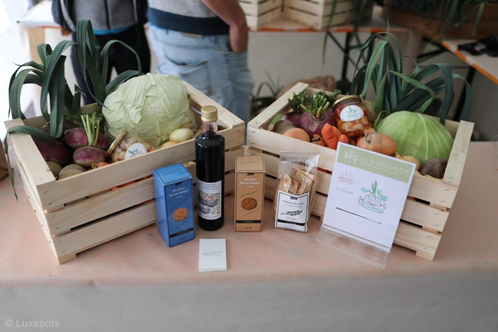 Auf einem Tisch sind Kisten mit Gemüse und verschiedenen verpackten Waren ausgestellt.