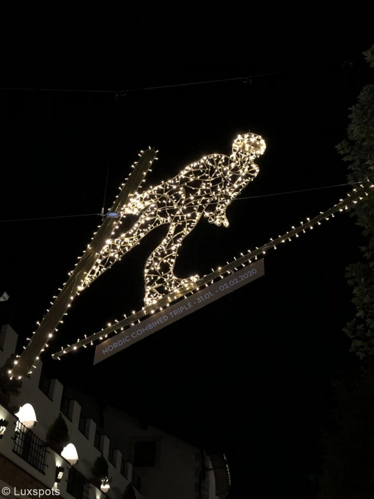 Eine beleuchtete Kunstinstallation zeigt einen Skispringer, der sich in der Luft befindet.